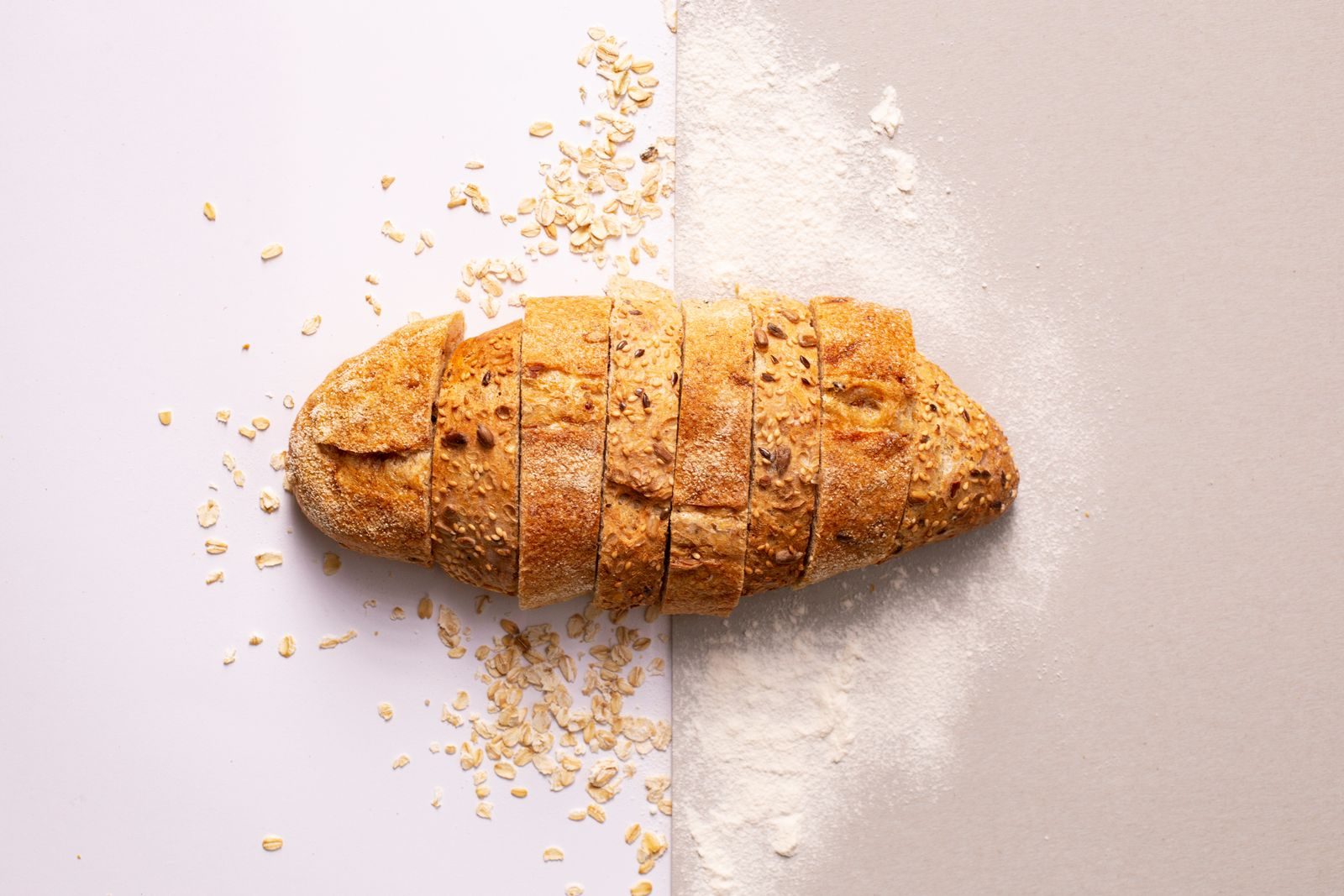 A cut loaf on a wooden board beside a knife.