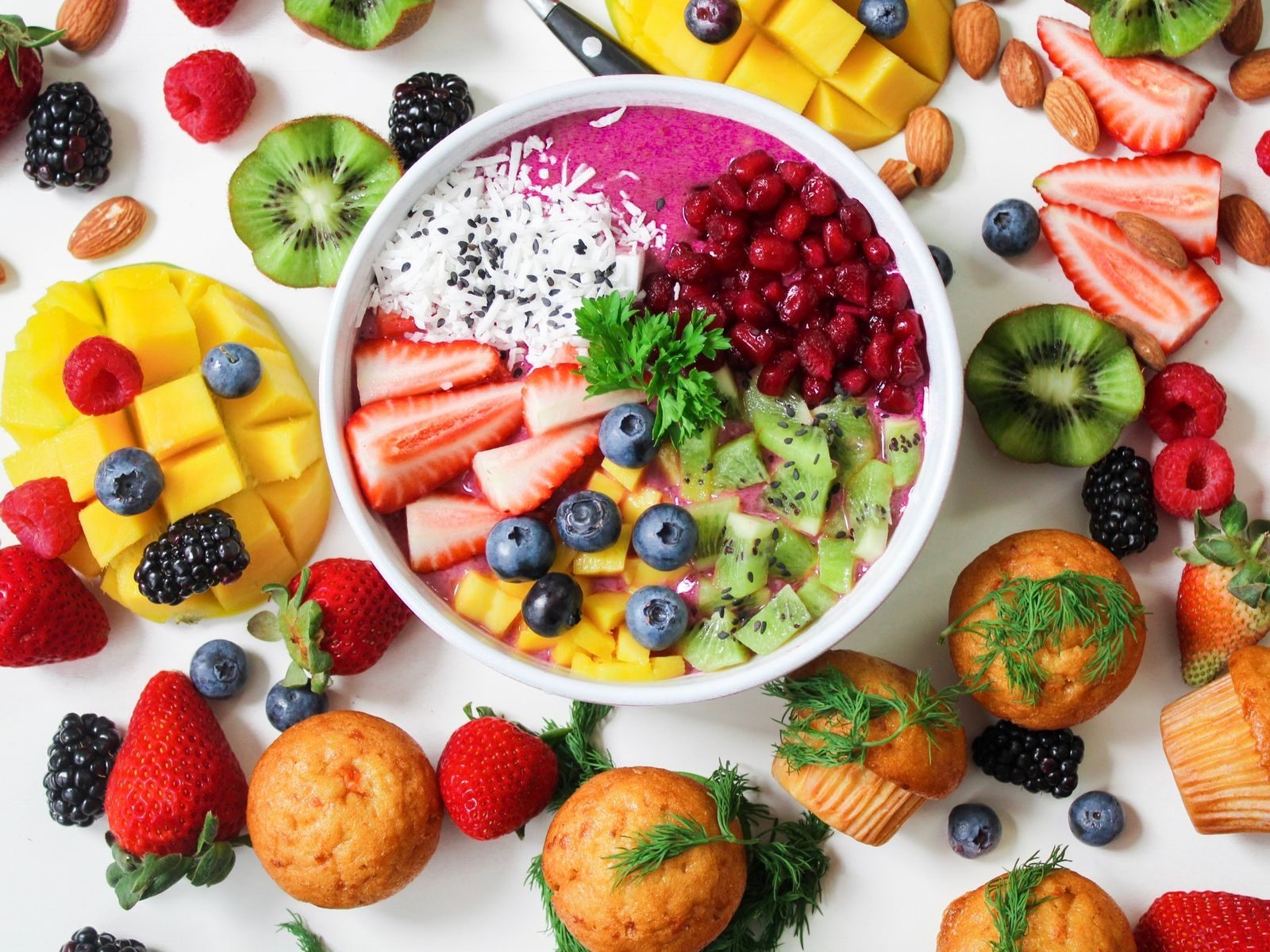 Green vegetables and fruit arranged in bowls.